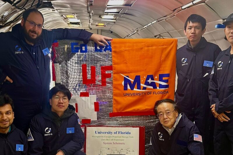 A group of six individuals in matching uniforms poses inside an aircraft, with banners from the University of Florida and MAE pinned on equipment.